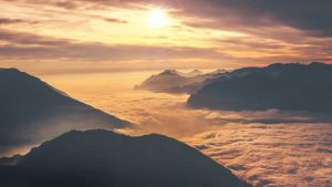 bilden visar sol över moln och berg