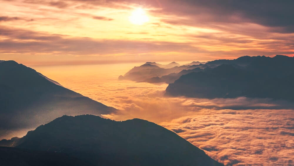 bilden visar sol över moln och berg