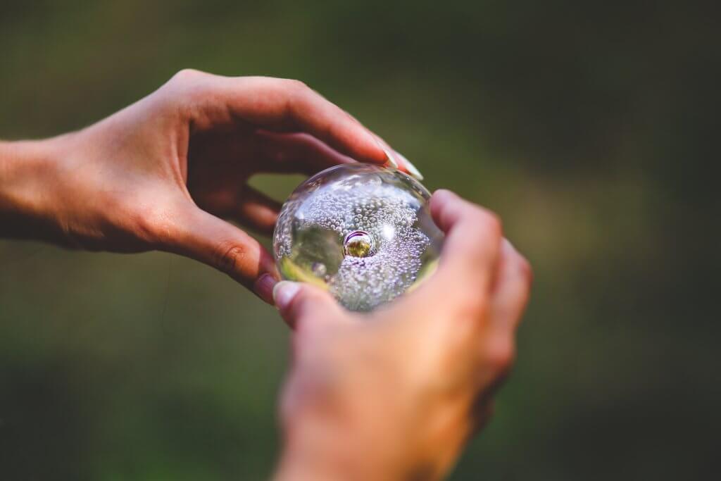 händer som håller en glasboll med luftbubblor